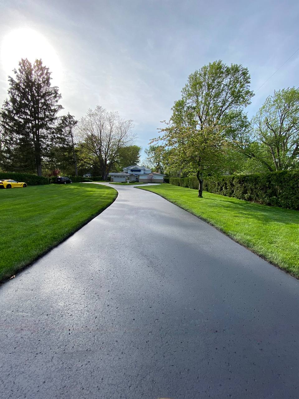 Smooth black sealcoated driveway bordered by green lawn